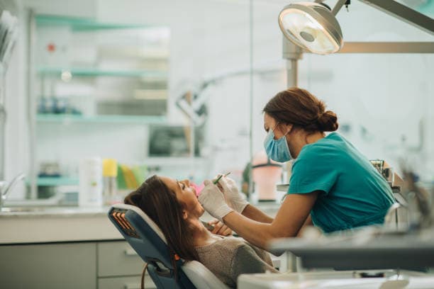 A dental clinician treating a patient in a clinic chair